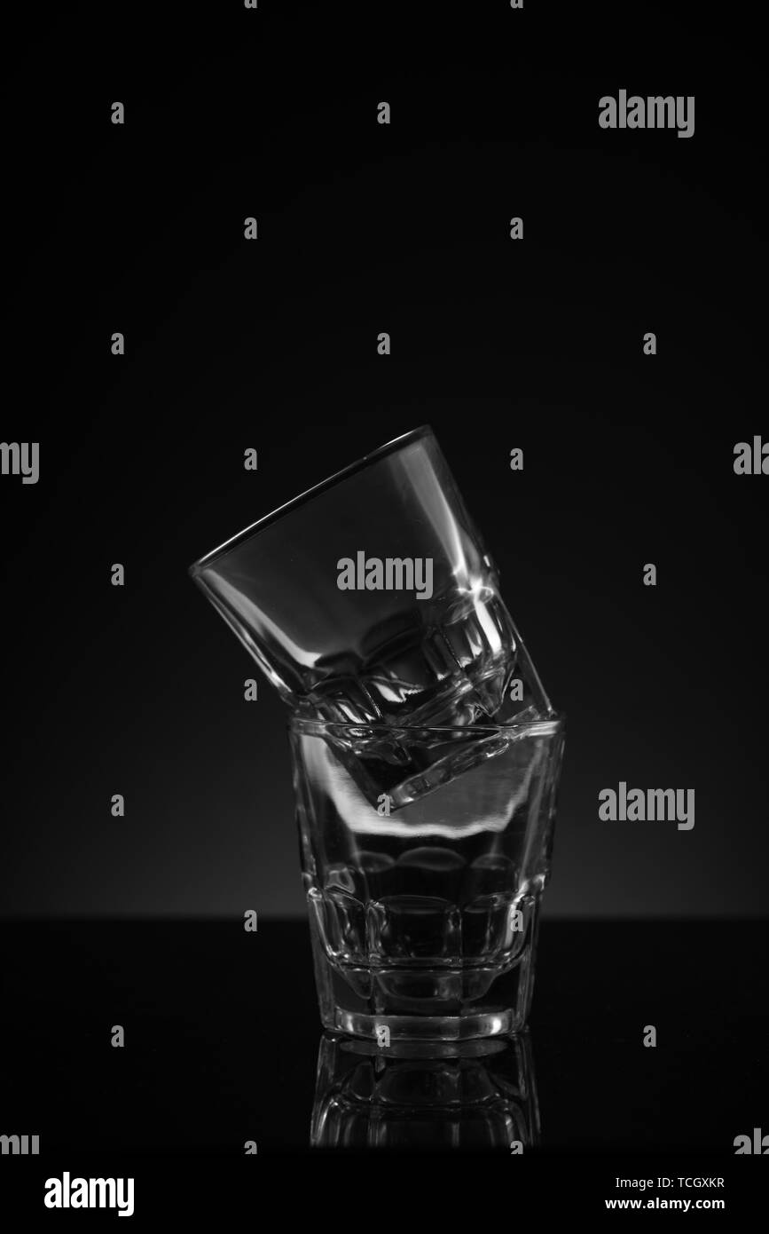 https://c8.alamy.com/comp/TCGXKR/stacked-clear-glass-shot-glasses-black-background-reflective-surface-and-awkward-arrangement-TCGXKR.jpg