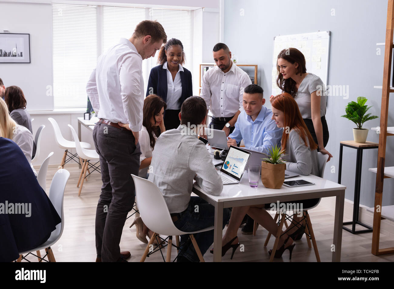 Group Of Young Diverse Business People Working And Communicating While Sitting At The Office Desk Stock Photo