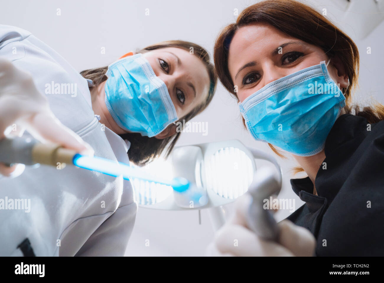 Bottom view of two women dentists in surgical mask holding tools and