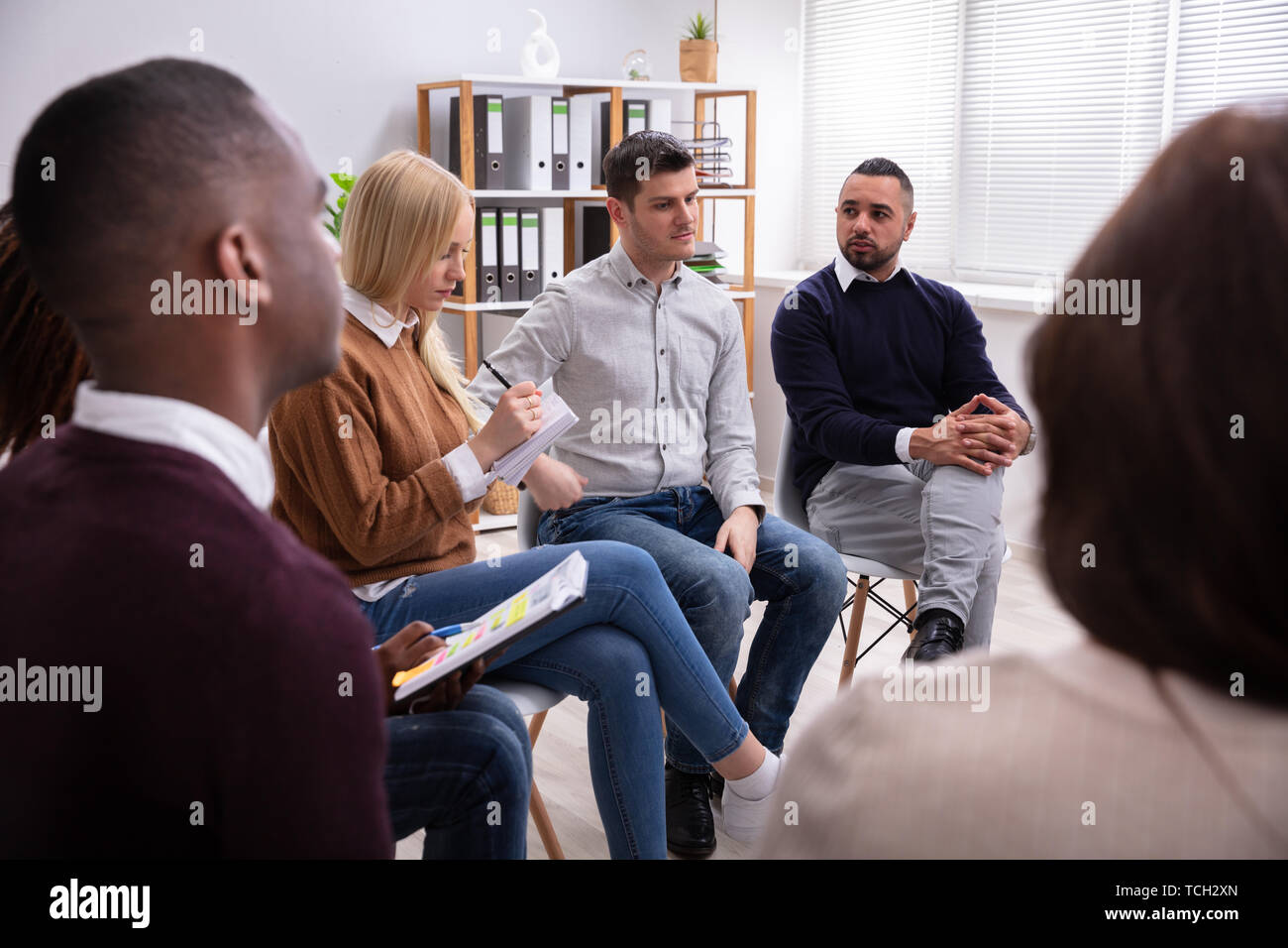 Smiling Men Looking At Their Male Friend While Discussion Stock Photo