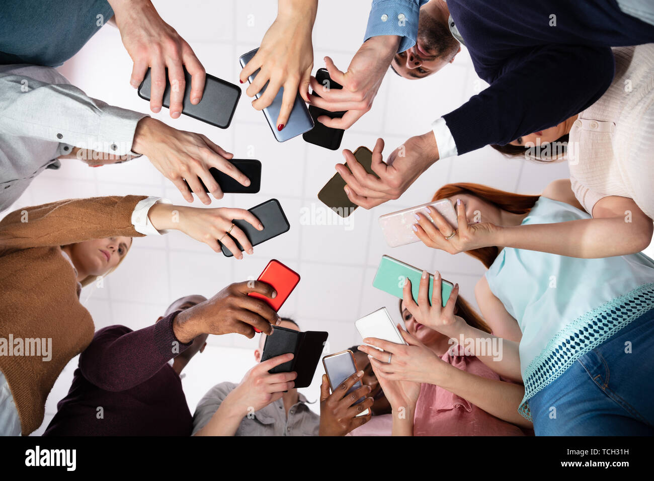Group Of People Standing In Circle Using Smartphone Stock Photo