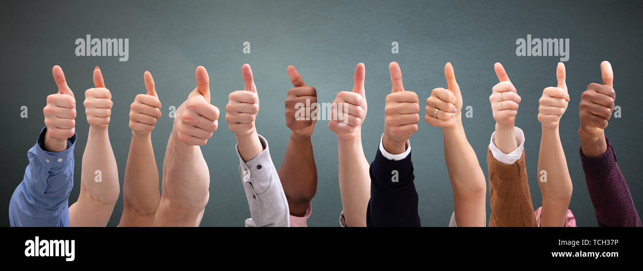 Close-up Of People's Hand Showing Thumb Up Sign Over Green Backdrop ...