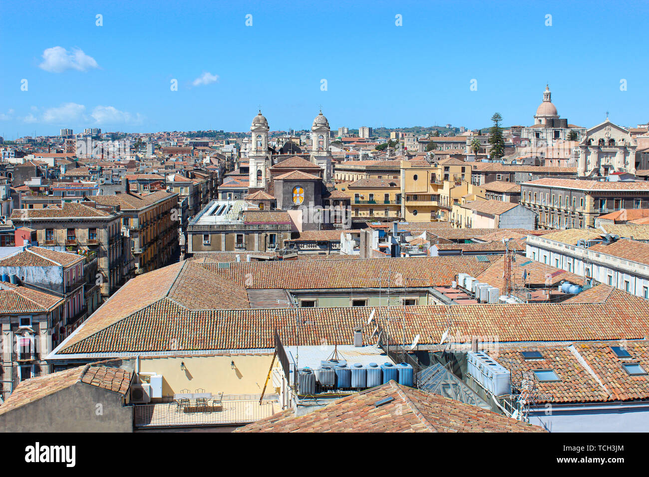 Beautiful cityscape of Sicilian city Catania, Italy taken from a view point above the city center. Catania has many historical sites and is a popular tourist attraction. Blue sky, sunny day. Stock Photo