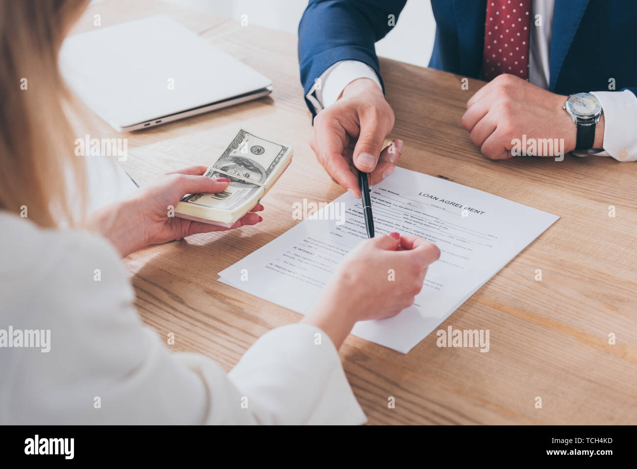 cropped shot of businessman pointing at signature place in loan agreement near woman holding dollar banknotes Stock Photo