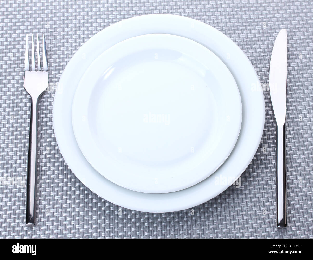 White empty plates with fork and knife on a grey tablecloth Stock Photo ...