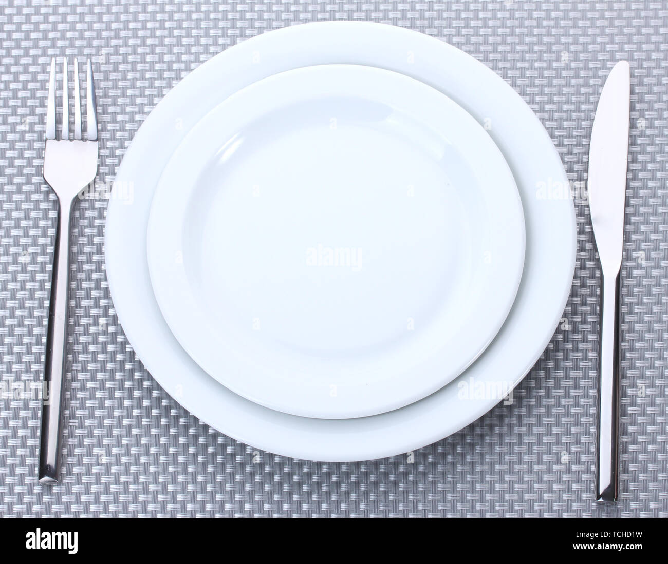 White empty plates with fork and knife on a grey tablecloth Stock Photo ...