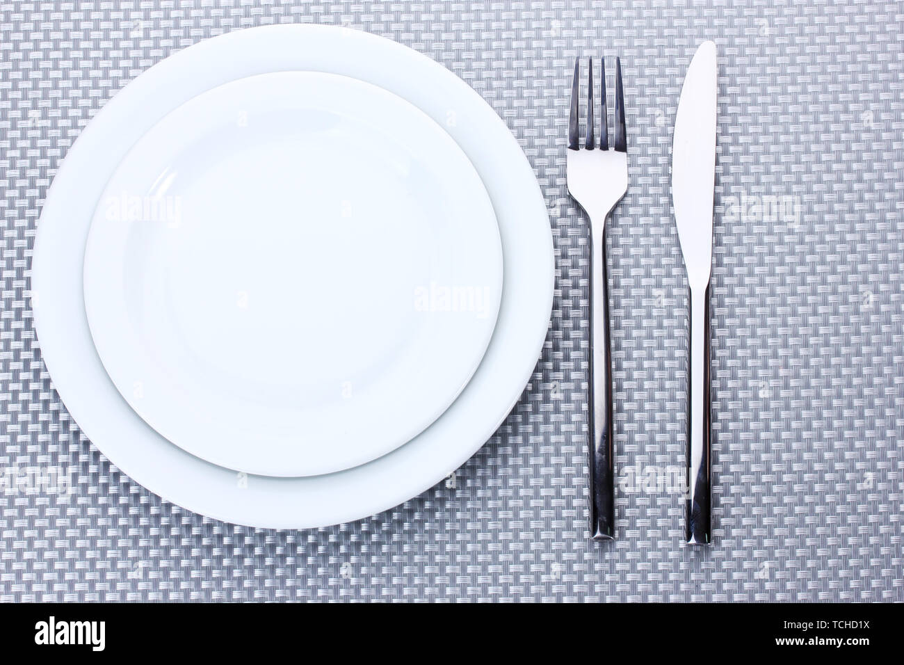 White empty plates with fork and knife on a grey tablecloth Stock Photo ...
