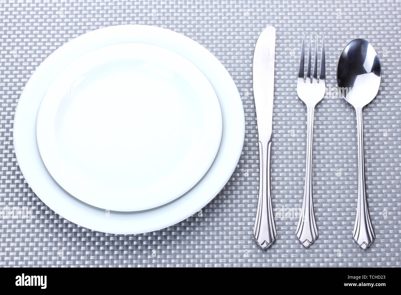 White empty plates with fork, spoon and knife on a grey tablecloth ...