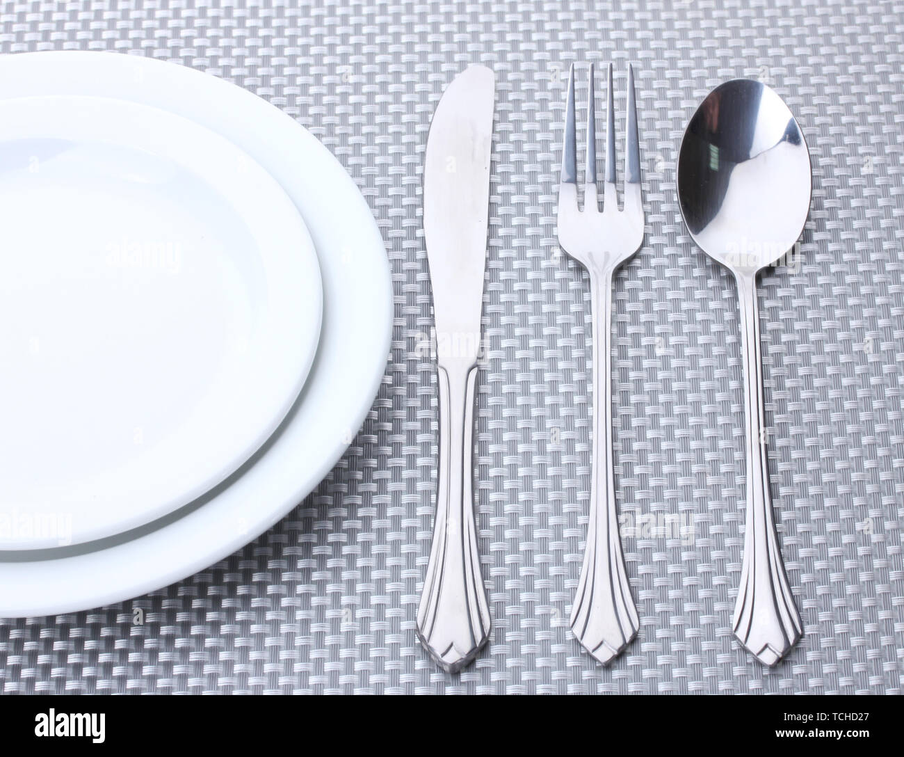 White empty plates with fork, spoon and knife on a grey tablecloth ...