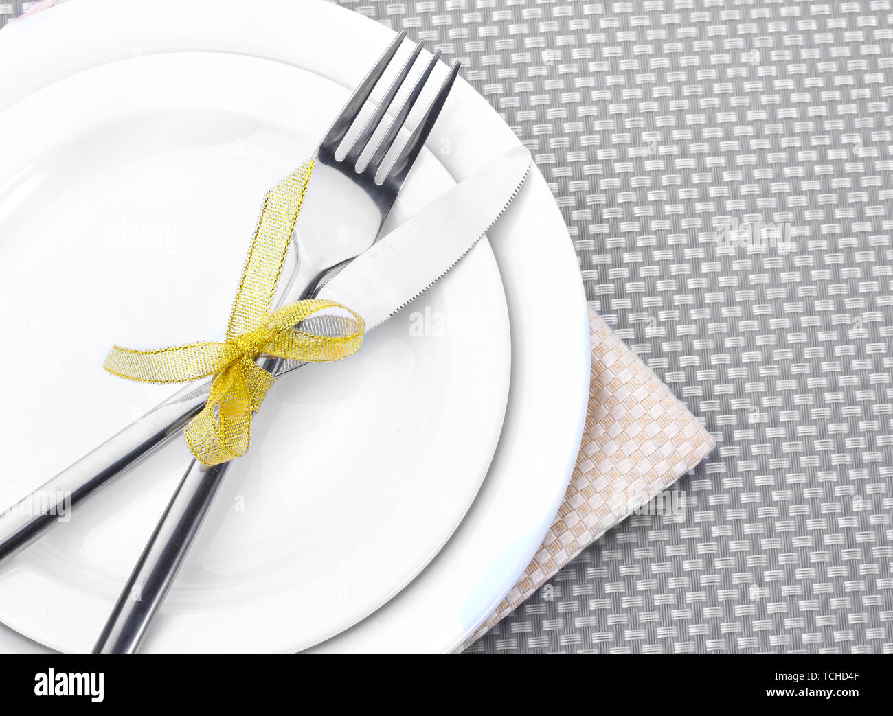 White empty plates with fork and knife tied with a ribbon on a grey ...