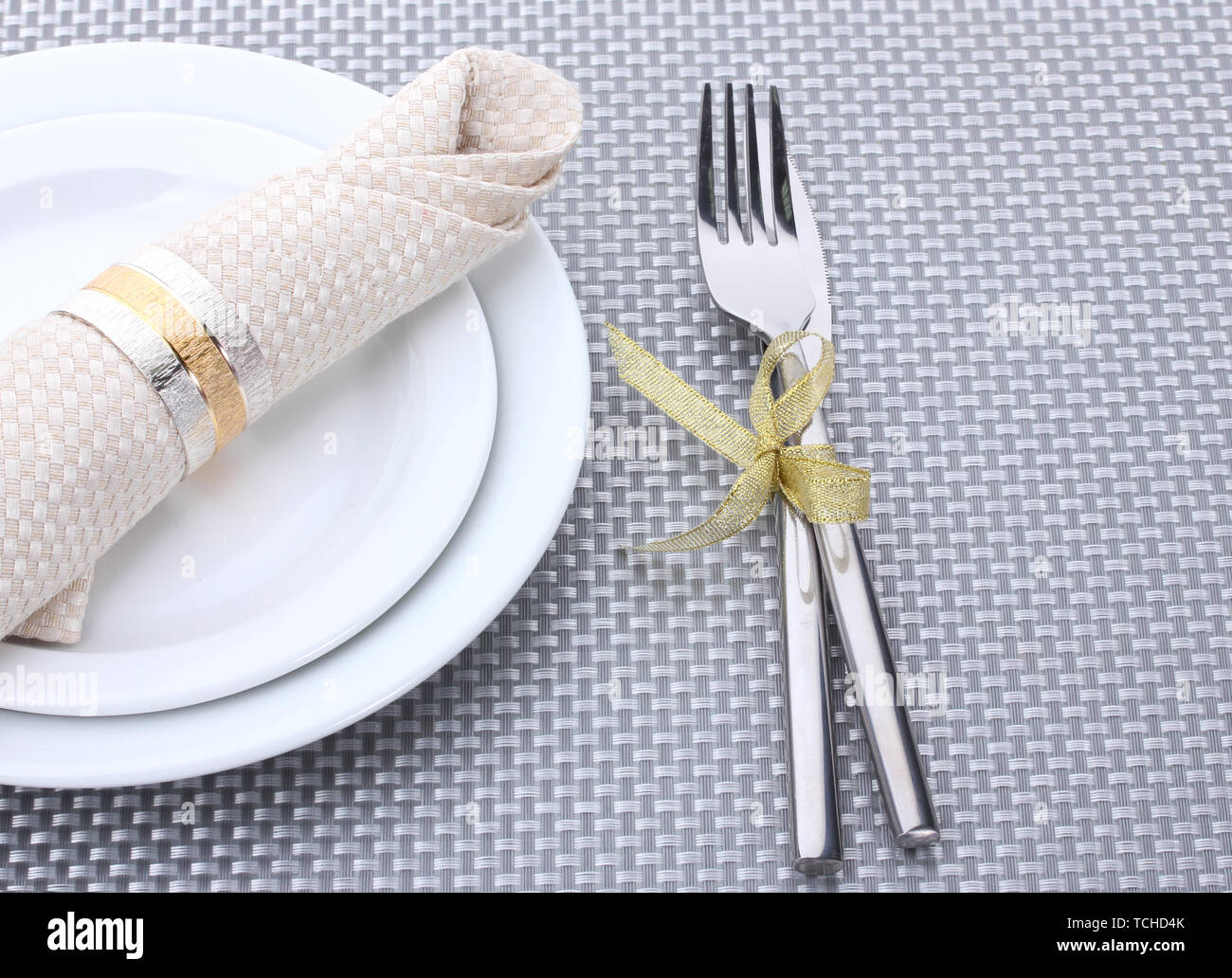 White empty plates with fork and knife tied with a ribbon on a grey ...