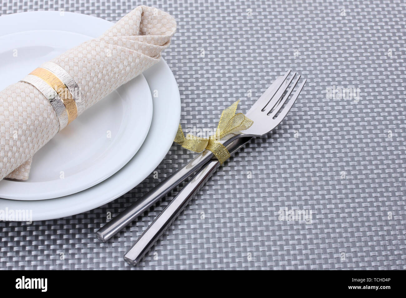 White empty plates with fork and knife tied with a ribbon on a grey ...