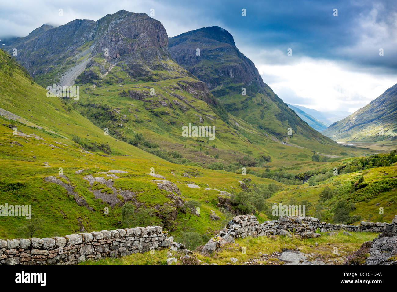 Stone wall and valley view below the mountains of Glencoe, Lochaber, HIghlands, Scotland Stock Photo
