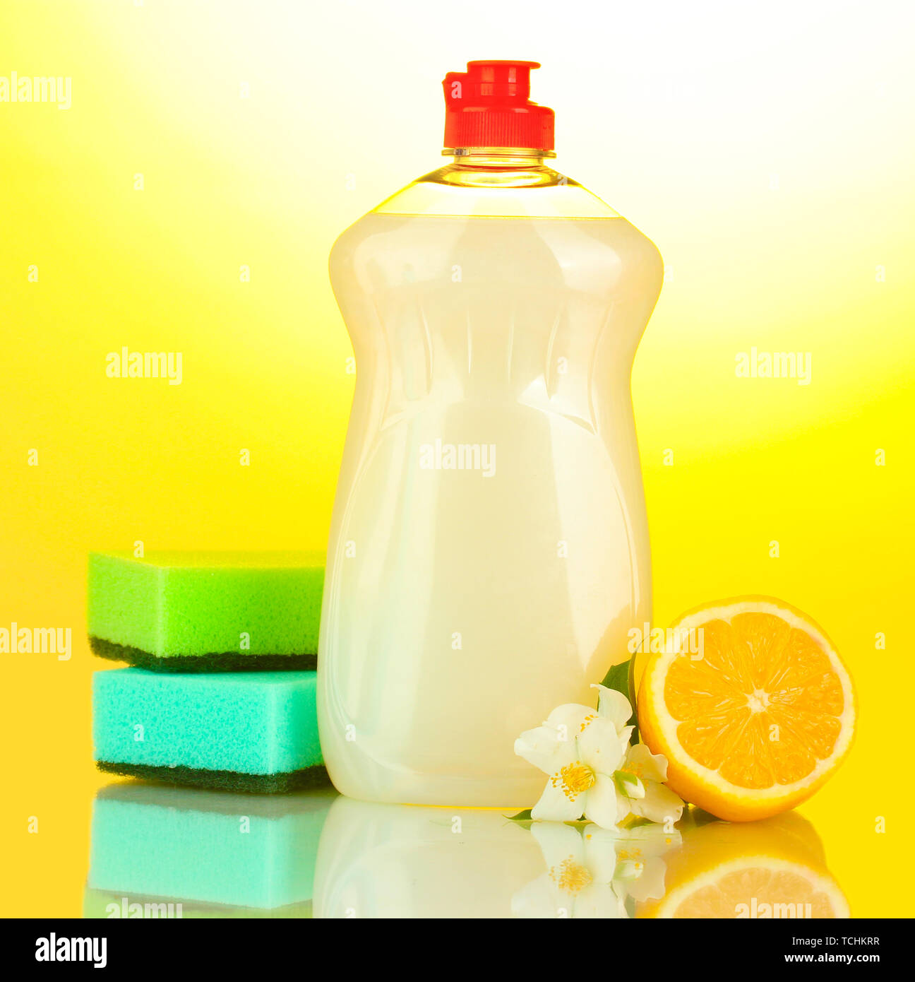 Dishwashing liquid with sponges and lemon with flowers on yellow