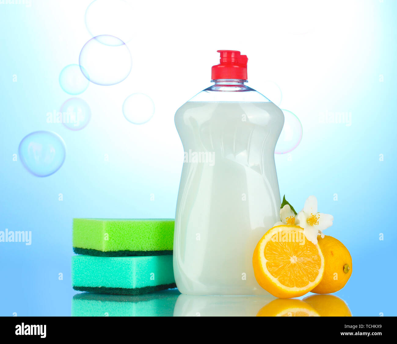 Dishwashing liquid with sponges and lemon with flowers on blue