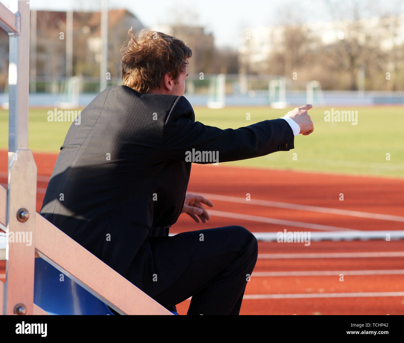 Spectator Trainer Coach sitting in Stadium in Front of Running Track