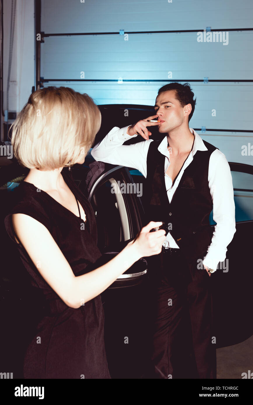 beautiful fashionable young woman holding lighter while handsome man smoking cigarette Stock Photo