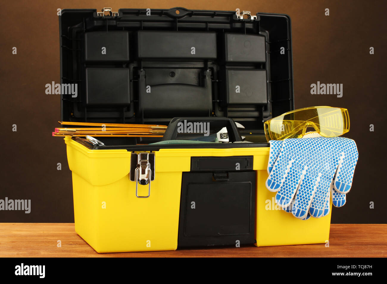Open yellow tool box with tools on brown background close-up Stock ...