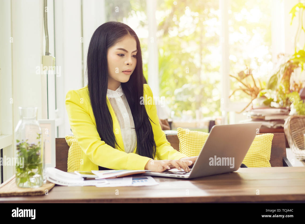 young beautiful Asian businesswoman sitting at table in coffee shop working with laptop Stock Photo