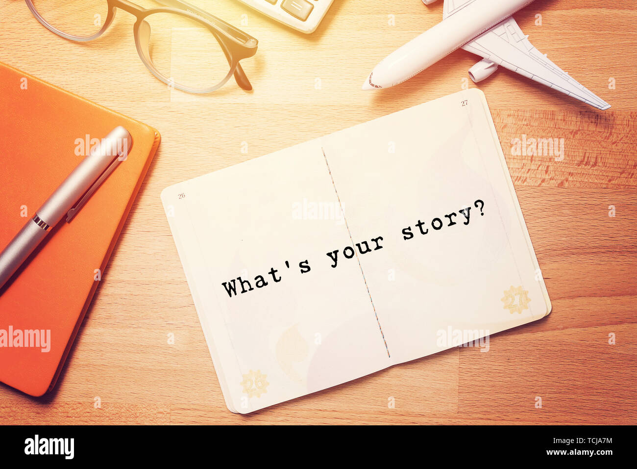 what's your story? notebook with text at blank page on wooden background with glasses and plane model Stock Photo
