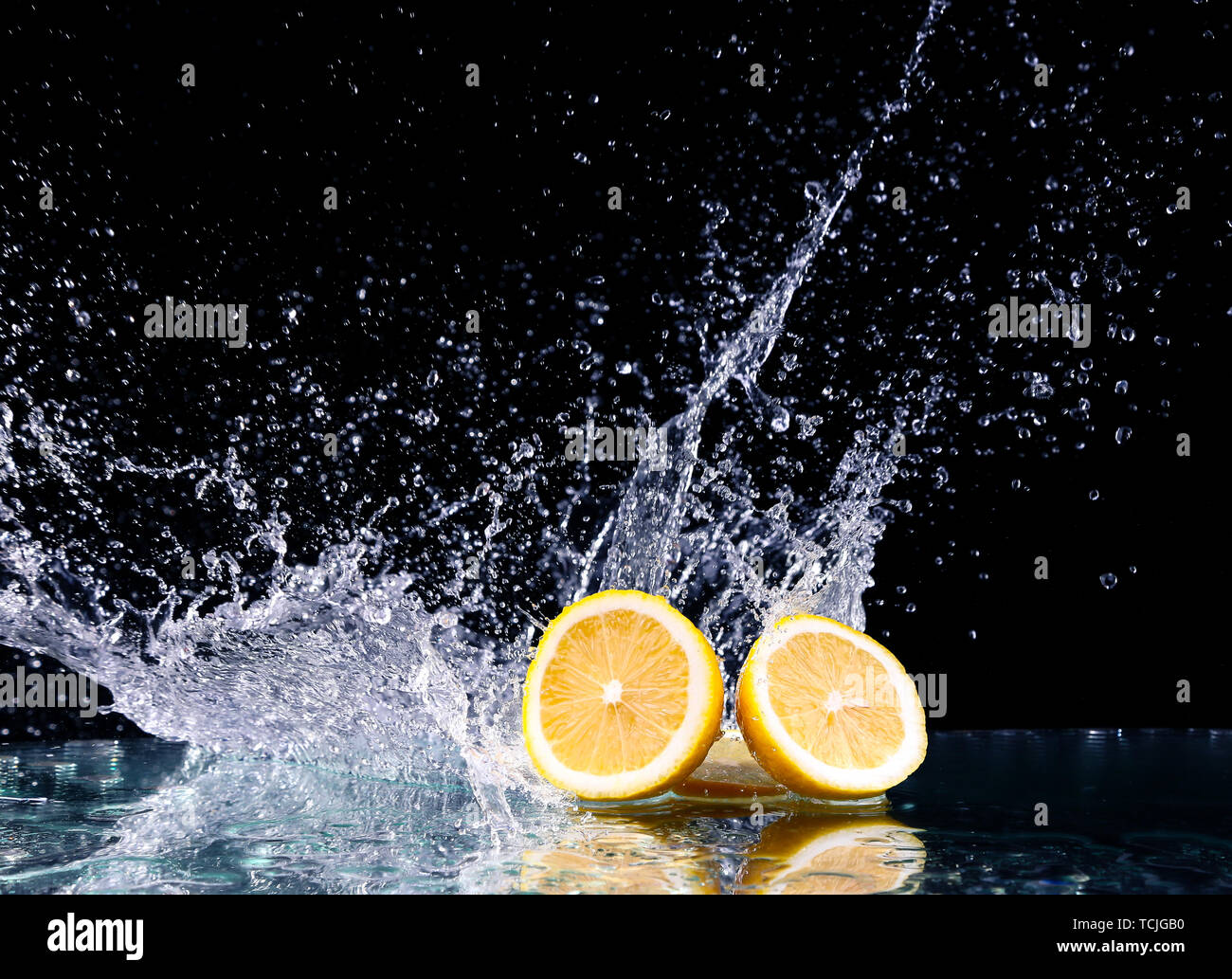 Splashed Lemon Sliced lemon in the water on black background. Fresh lemons with water ...
