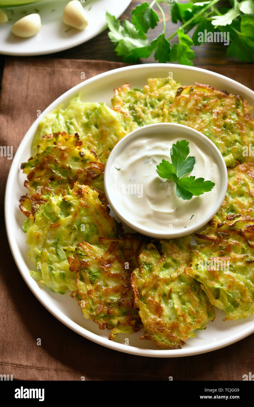 Close up of zucchini fritters (vegetable pancakes) with sauce on white ...