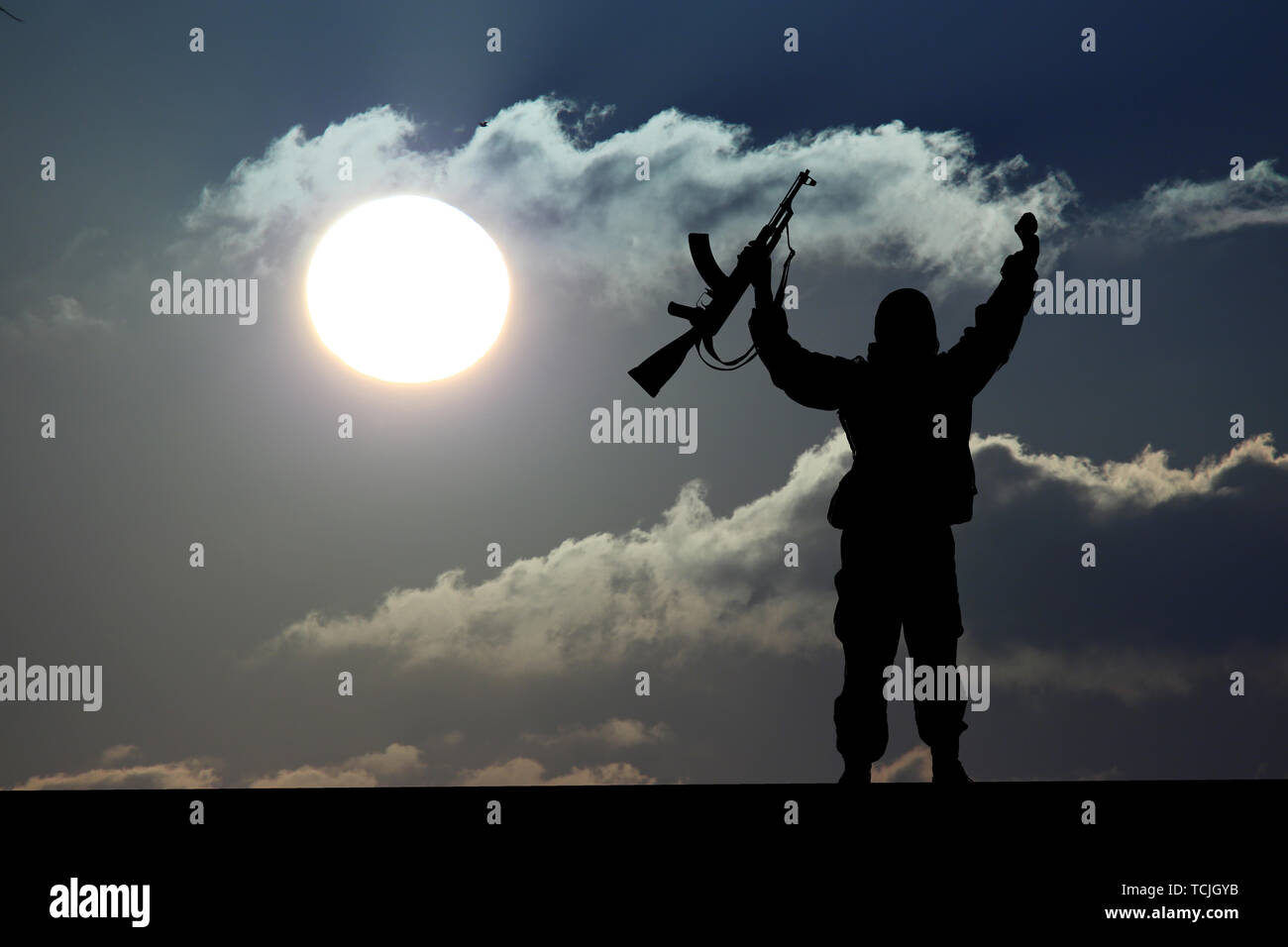 Silhouette of military soldier or officer with weapons at sunset. shot, holding gun, colorful sky, Concept of a terrorist. Silhouette terrorists with  Stock Photo