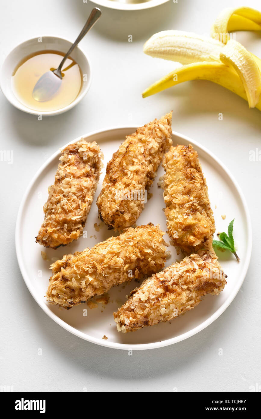 Deep fried bananas on plate over white stone background. Tasty dessert