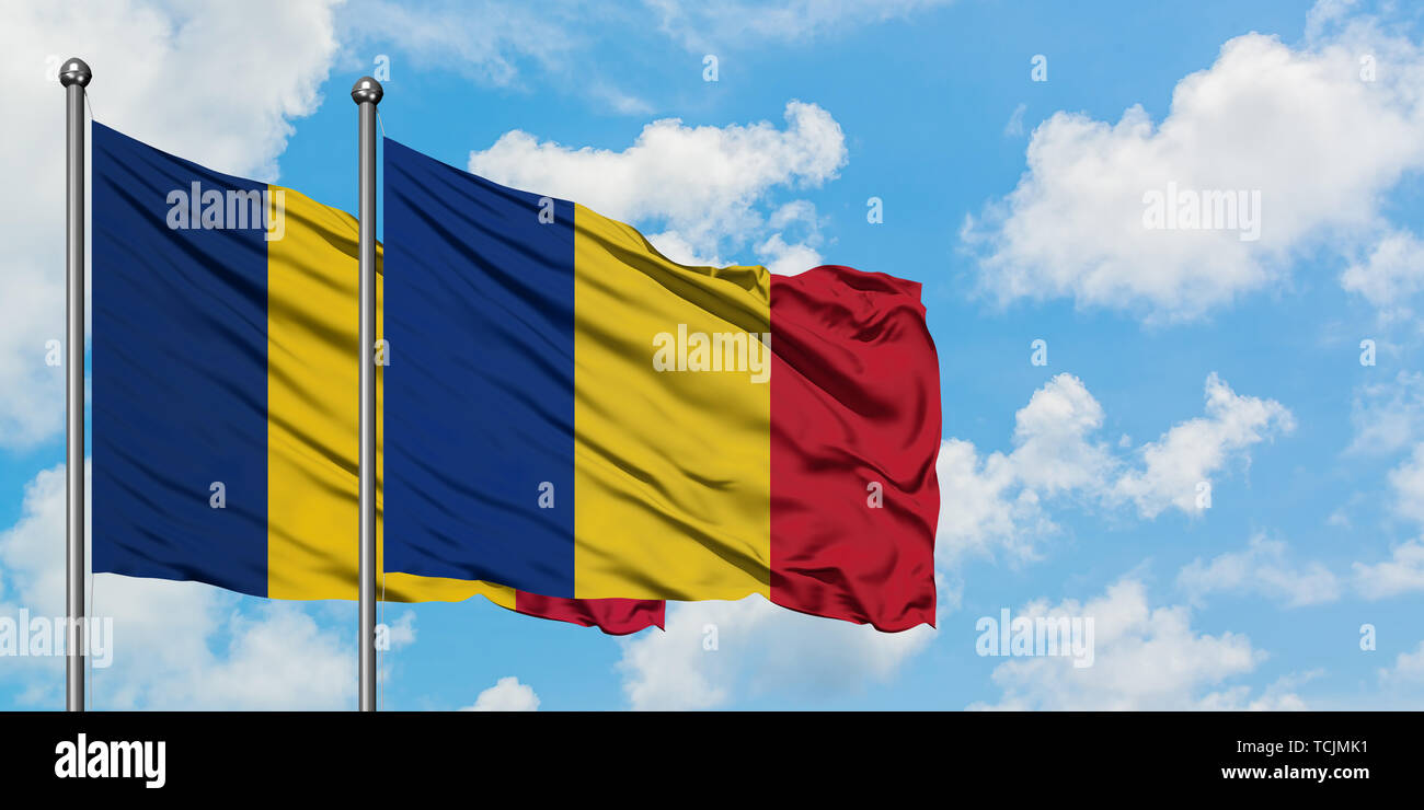 Chad and Romania flag waving in the wind against white cloudy blue sky together. Diplomacy
