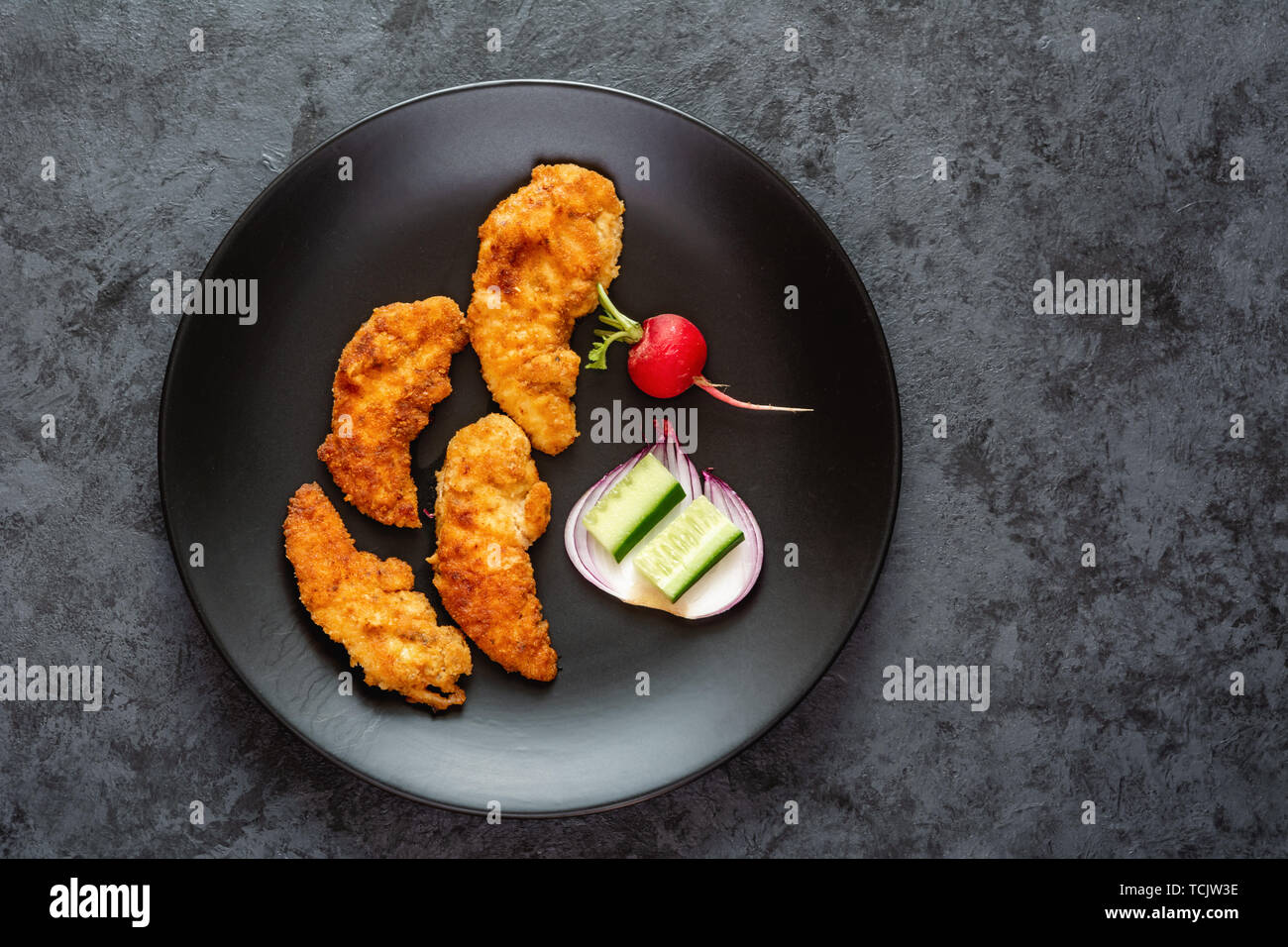 Fried chicken sirloin in breadcrumbs on a black dish. Stock Photo