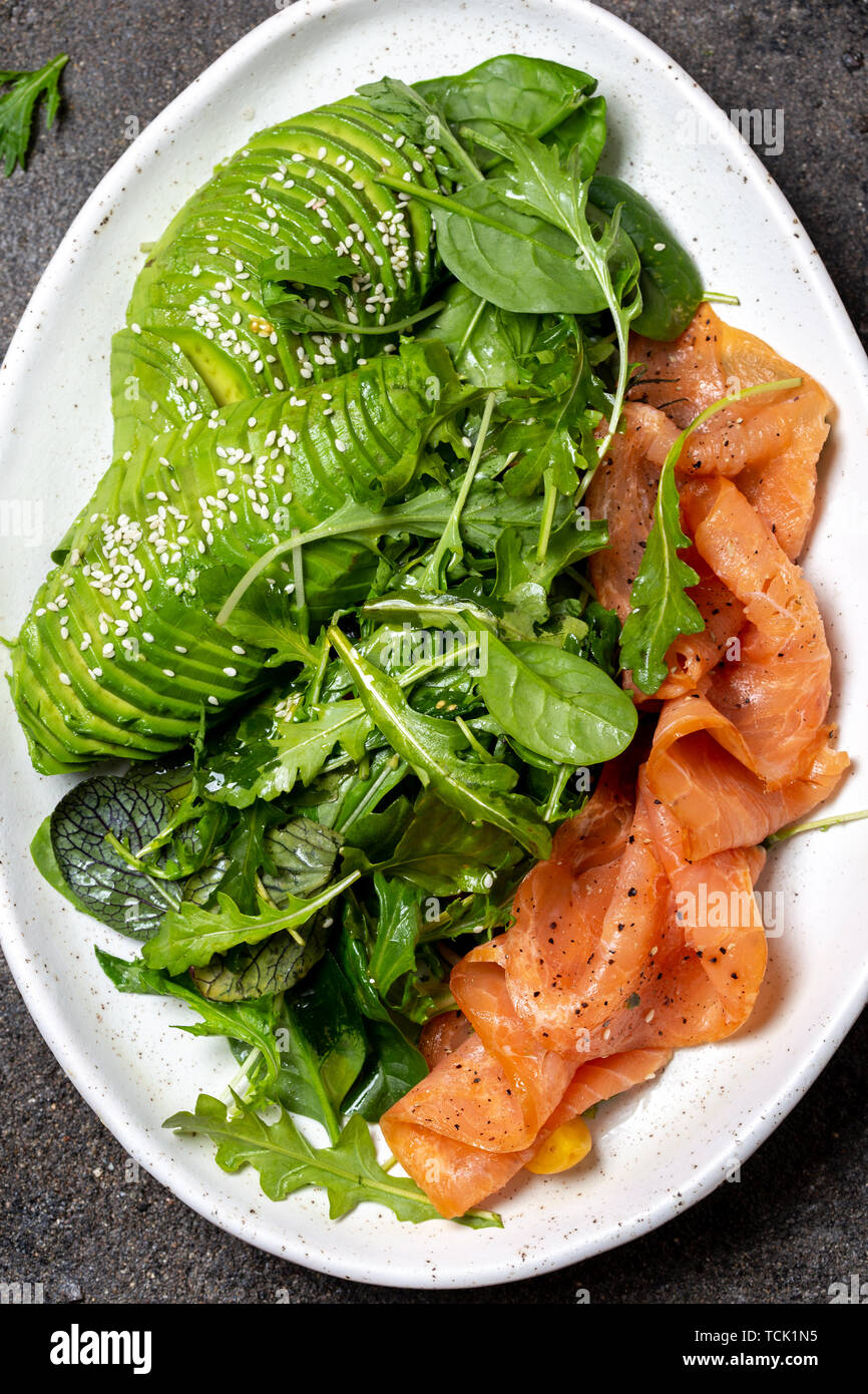 Low carbs salad. Spinach, rucola salad with avocado and salmon. Black