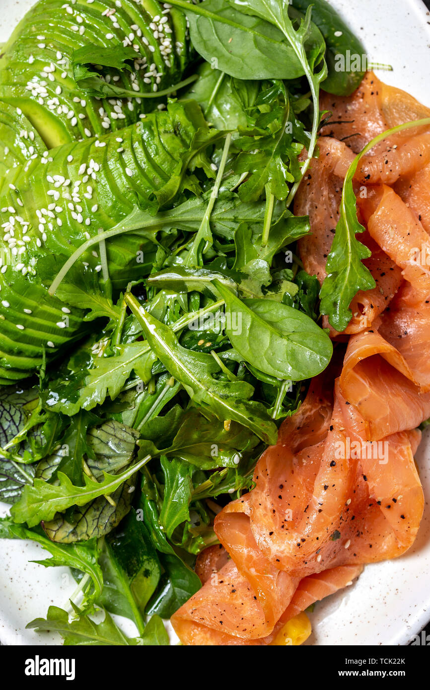 Low carbs salad. Spinach, rucola salad with avocado and salmon. Black