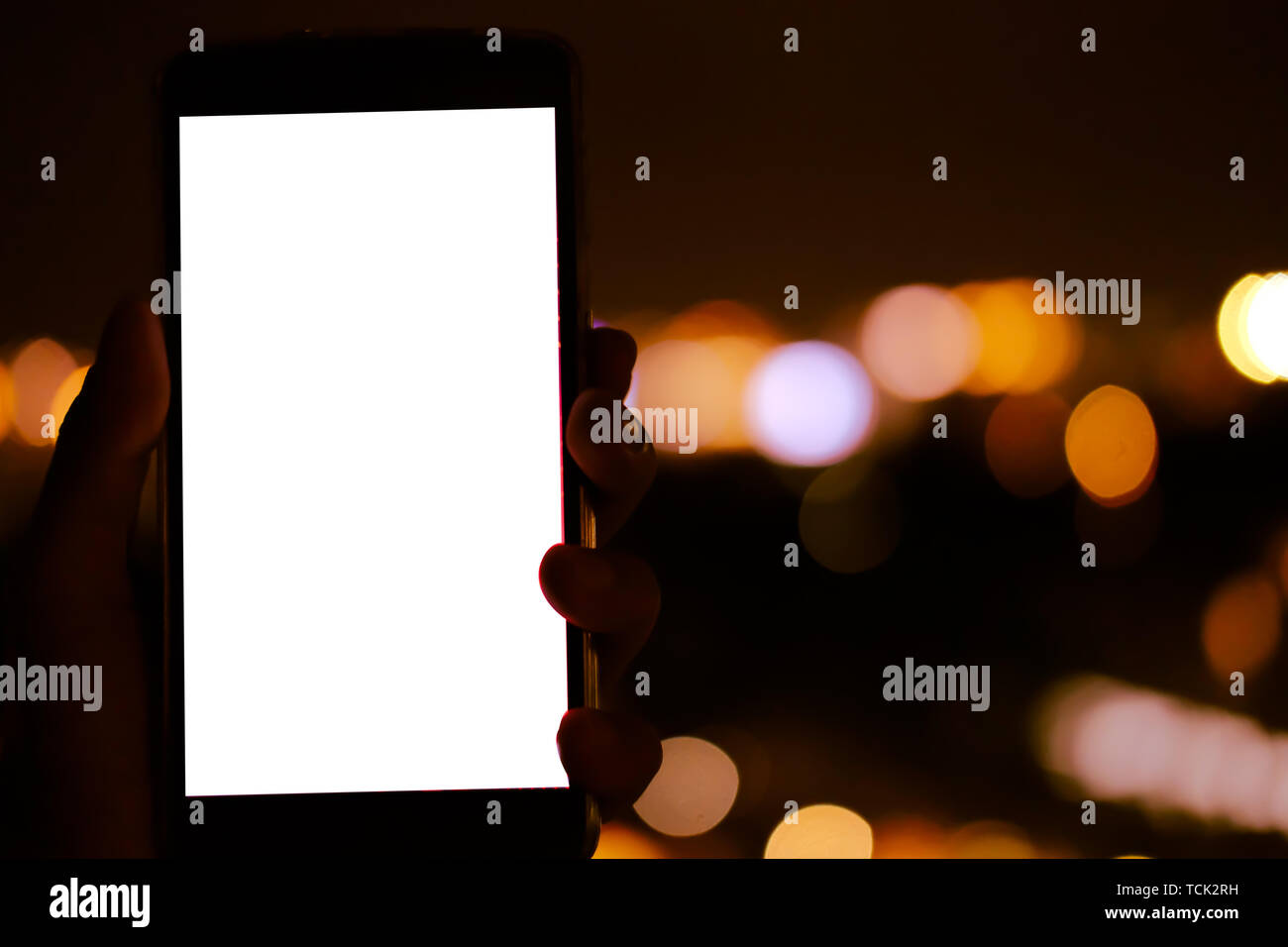 hand holding mobile smart phone with blank screen with bokeh night ...