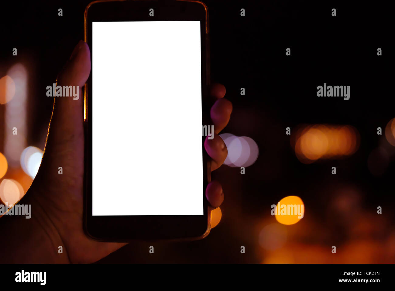 hand holding mobile smart phone with blank screen with bokeh night ...