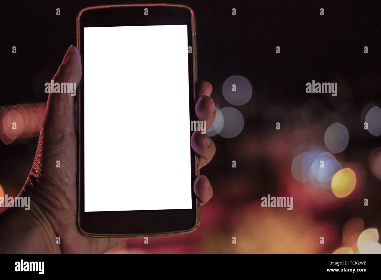 hand holding mobile smart phone with blank screen with bokeh night ...