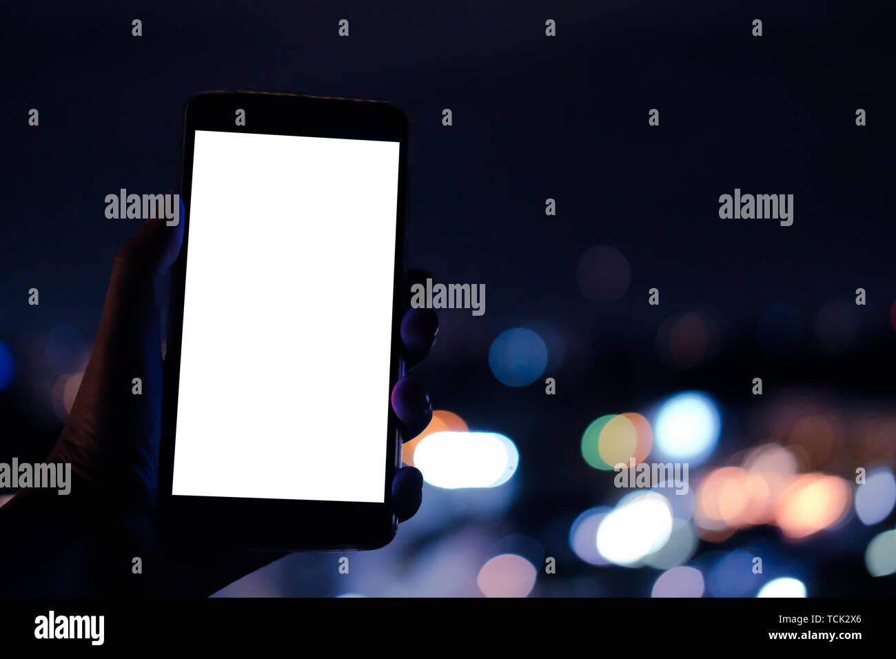 hand holding mobile smart phone with blank screen with bokeh night ...