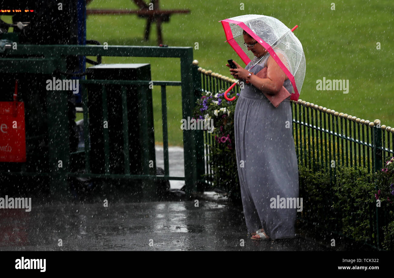 A racegoer braves the bad conditions during Betway Sparkling Saturday at Haydock Park Racecourse, Newton-Le-Willows. Stock Photo