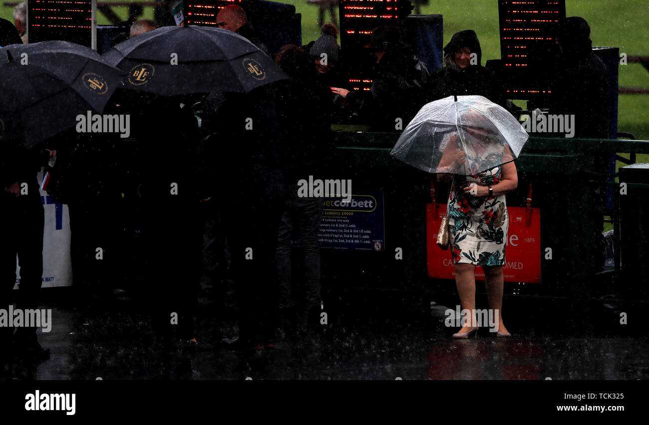 A racegoer runs back in the bad conditions after placing a bet during Betway Sparkling Saturday at Haydock Park Racecourse, Newton-Le-Willows. Stock Photo
