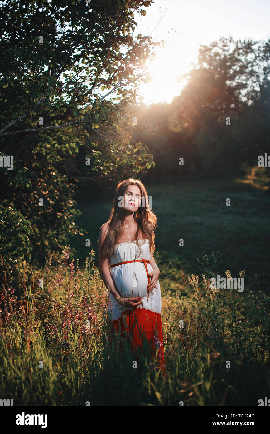 Calm pregnant woman in third trimester. Walking in public garden. Sunset in  the forest Stock Photo - Alamy