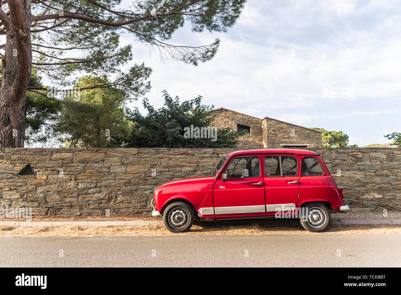 Red Renault R4 stands at a street in front of a stone wall in St. Florent, Corsica, France Stock Photo