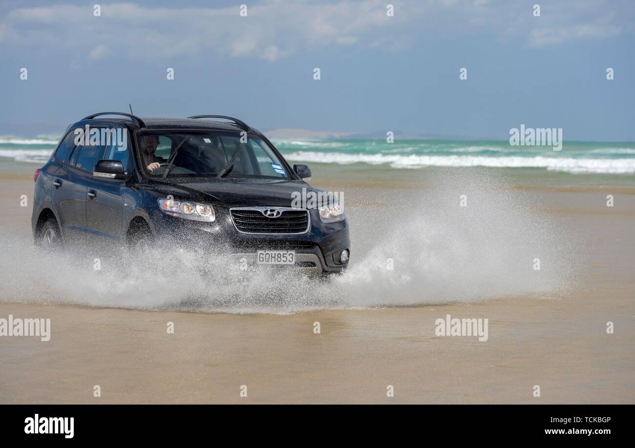 Black Hyundai Santa Fe 4x4 off-road vehicle drives on the sandy beach of Ninety Mile Beach in the water, Far North District, Northland, North Island Stock Photo