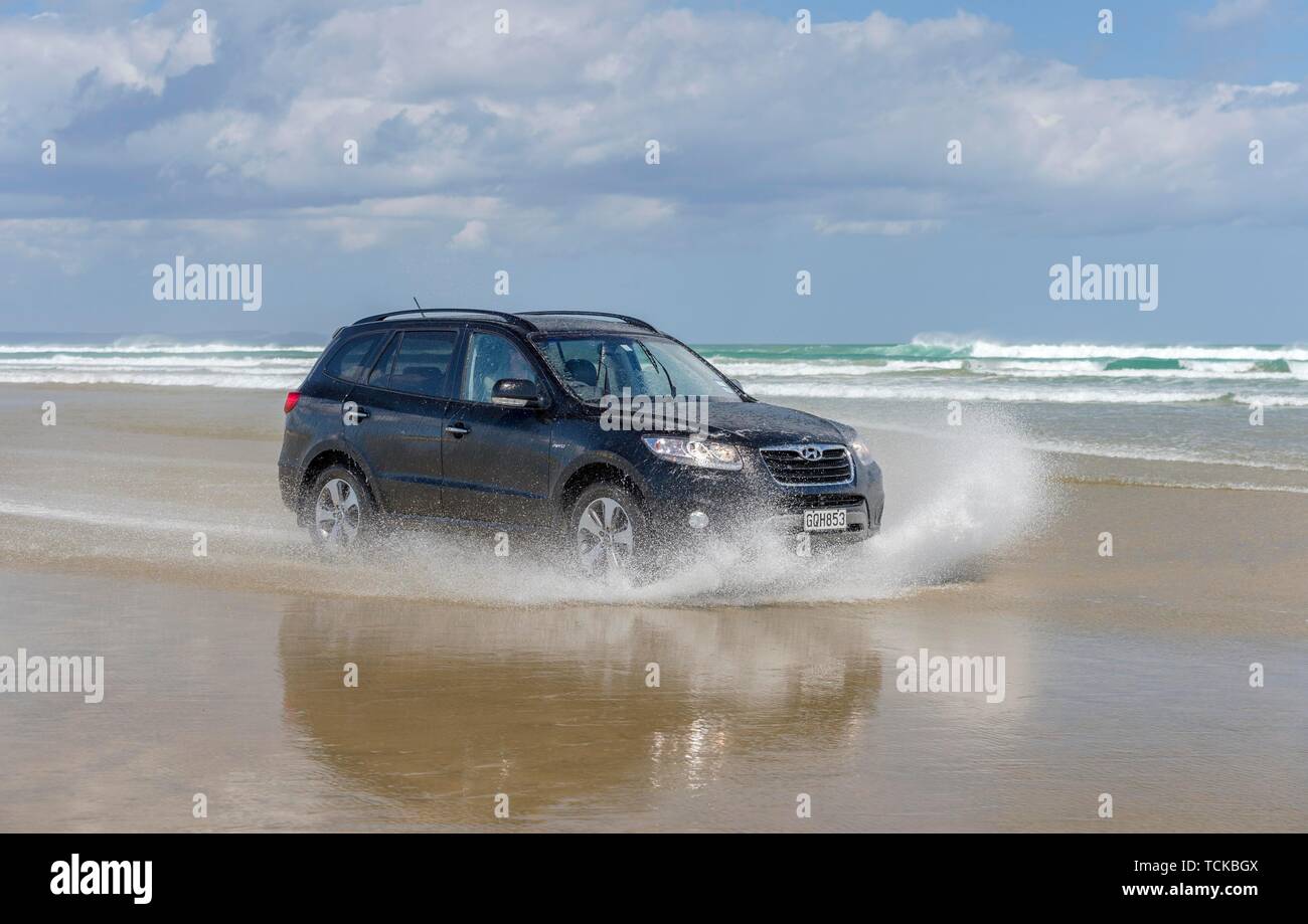 Black Hyundai Santa Fe 4x4 off-road vehicle drives on the sandy beach of Ninety Mile Beach in the water, Far North District, Northland, North Island Stock Photo