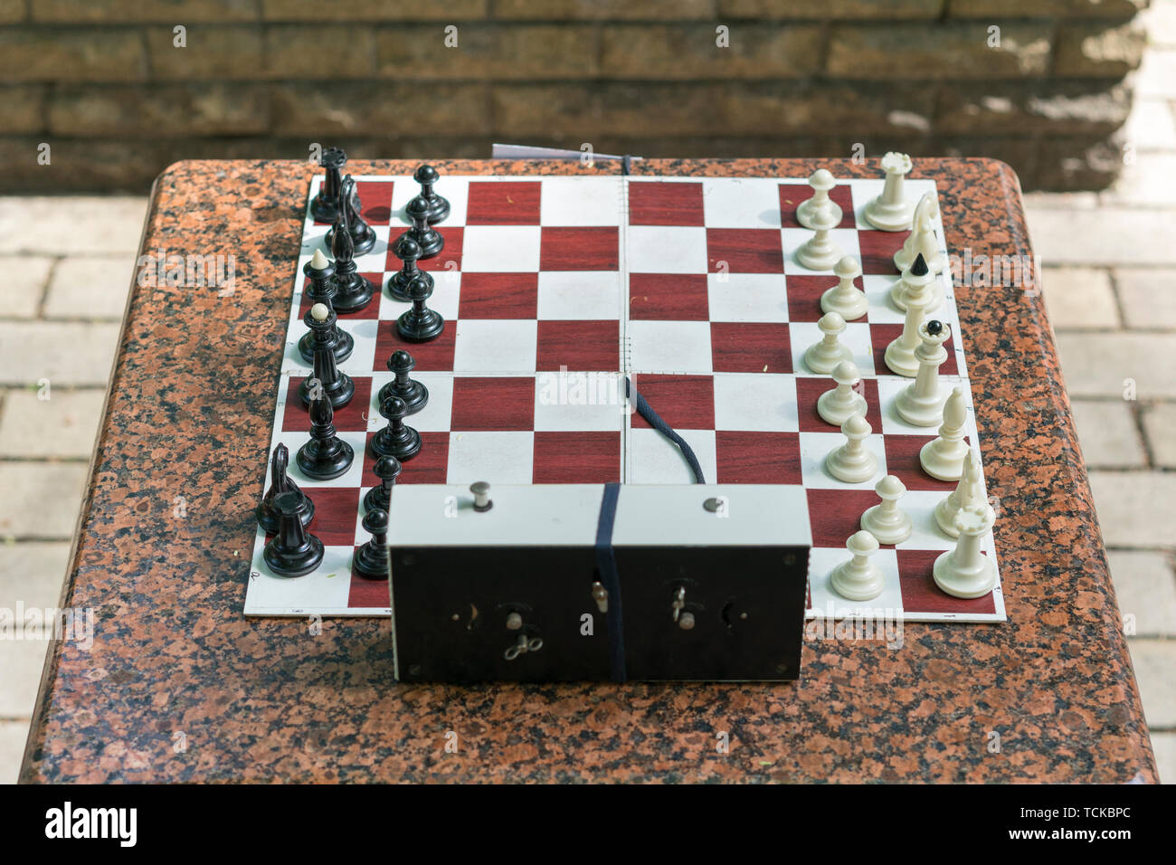 Chess board with pieces and clock on wooden desk In connection with the