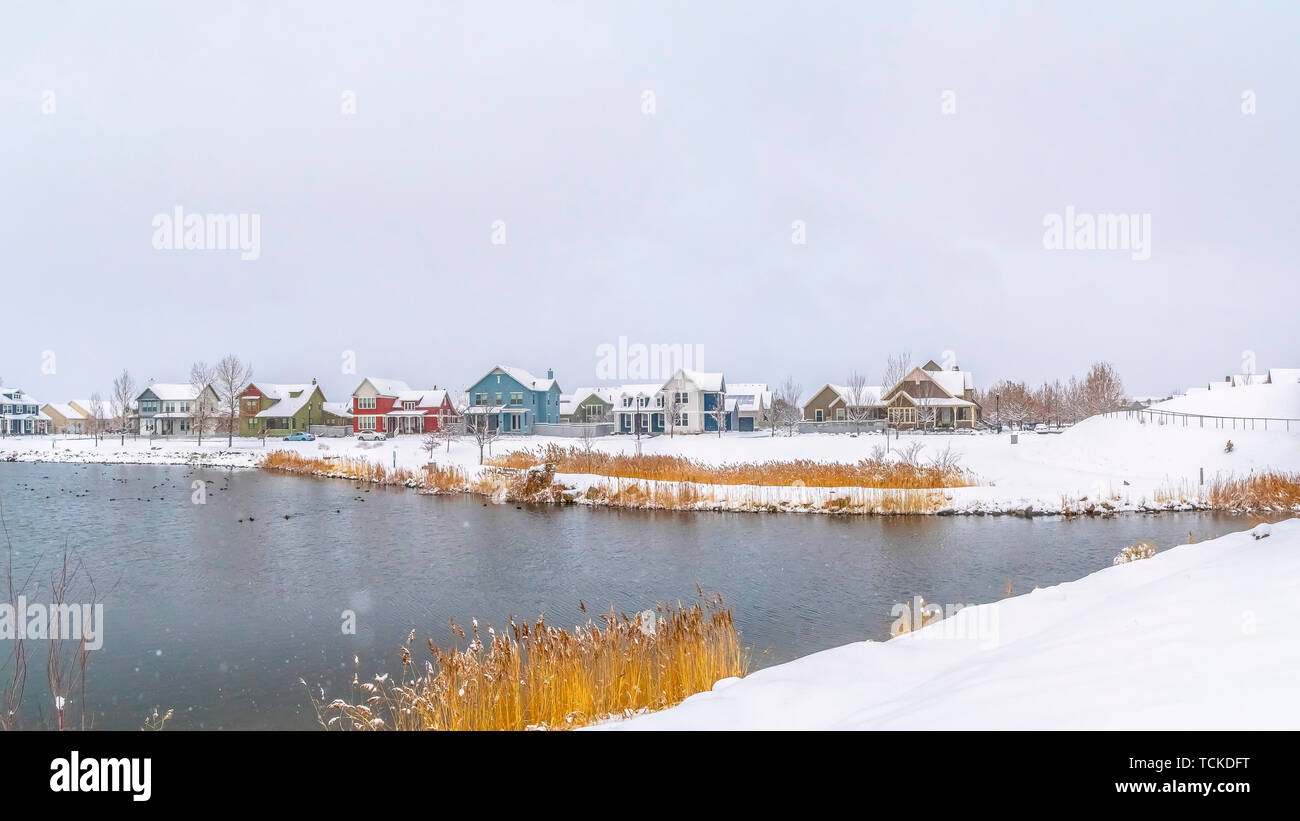 Panorama frame Panorama of a silvery lake with distant houses against cloudy sky in winter Stock Photo