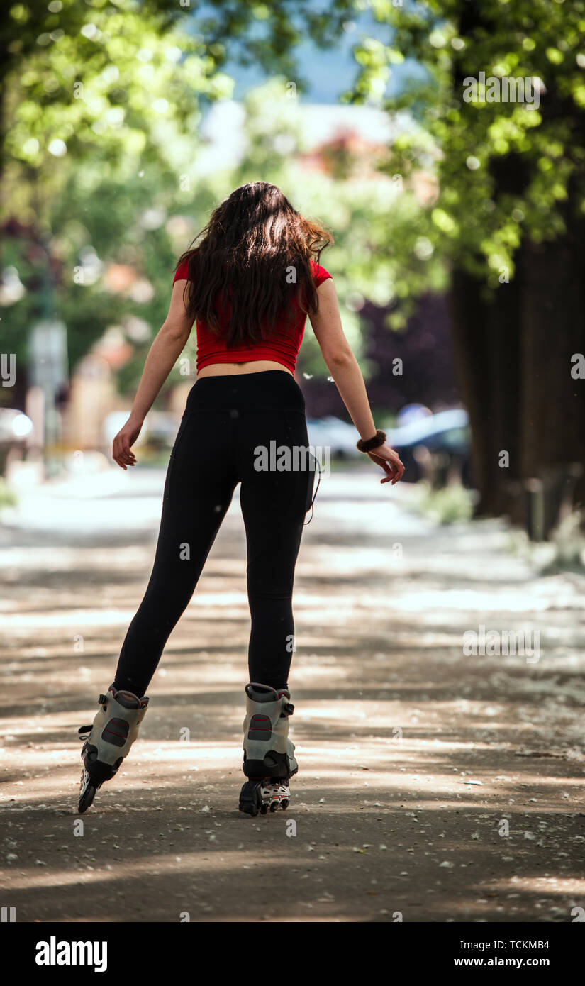 Happy woman roller skating sport in park sunny day while listening music on  headphones Stock Photo - Alamy