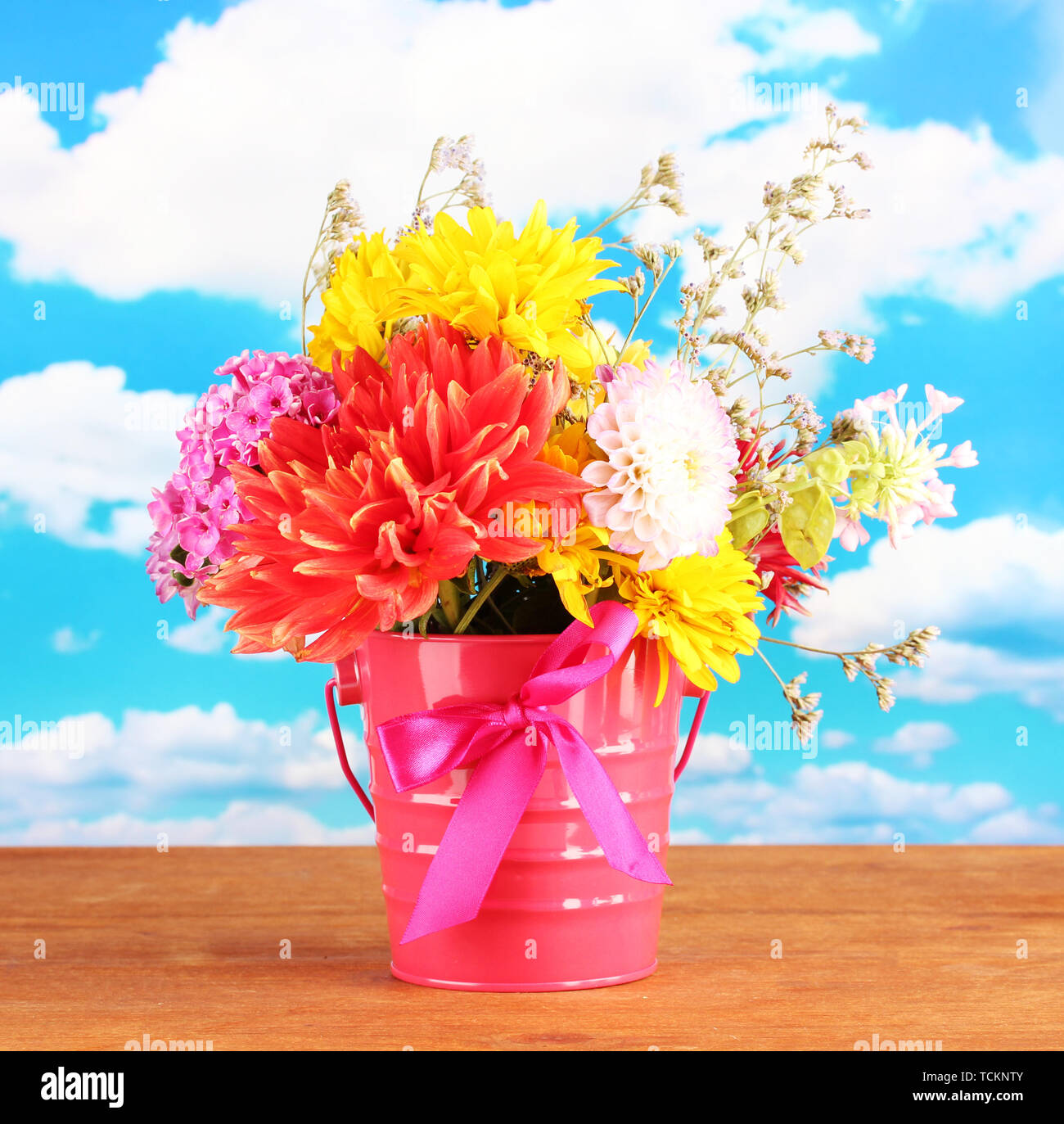 Bright pink bucket with flowers on sky background Stock Photo - Alamy