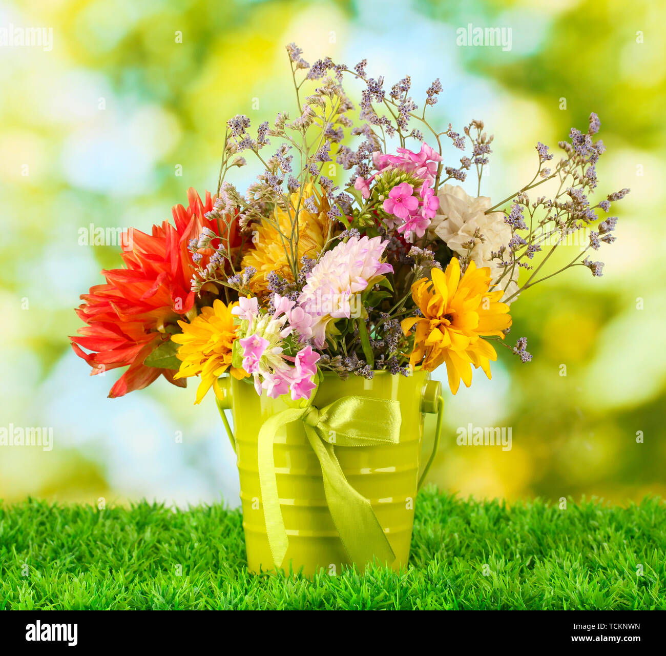 Bright green bucket with flowers on green background Stock Photo Alamy