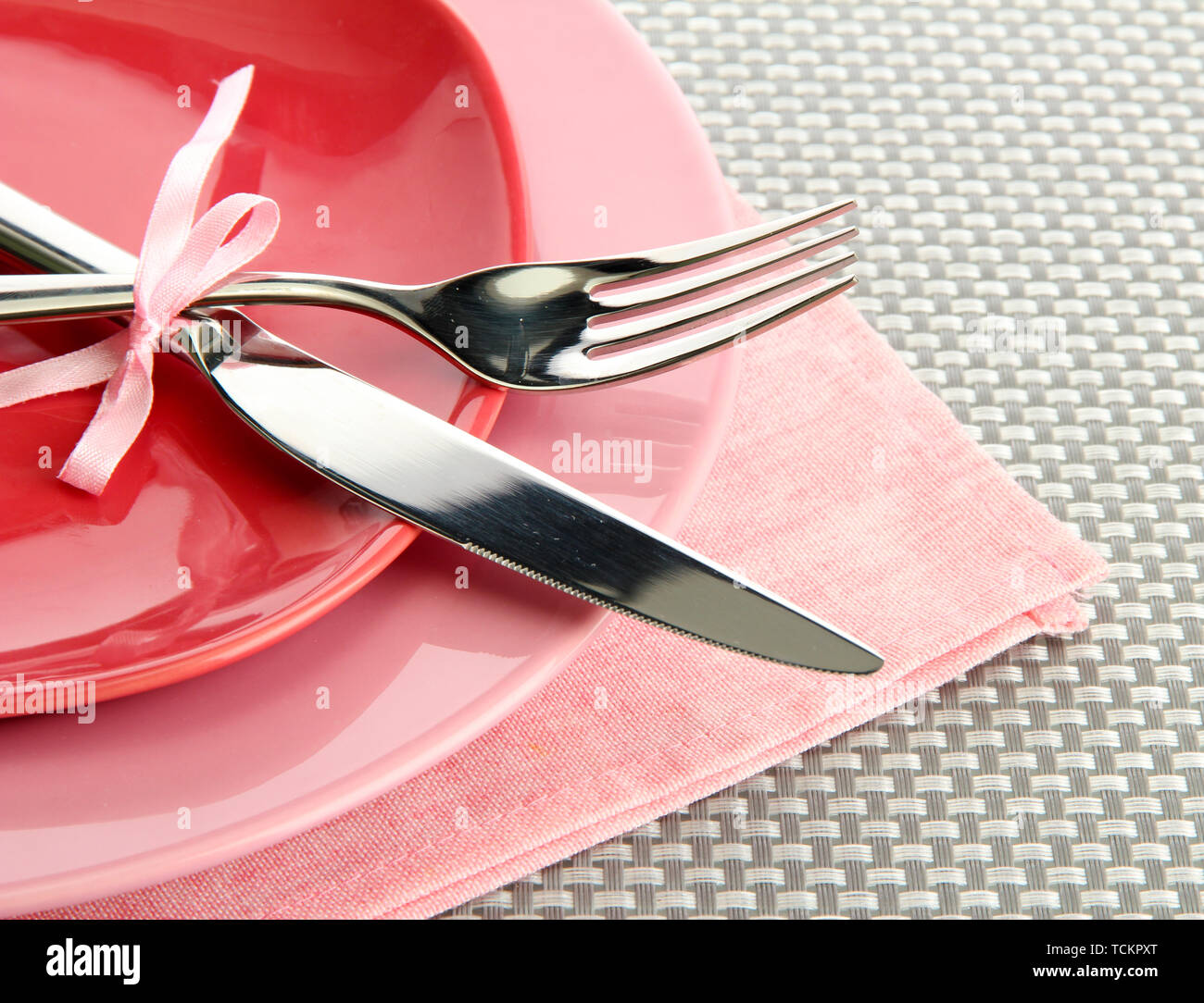 Pink empty plates with fork and knife on a grey tablecloth Stock Photo ...