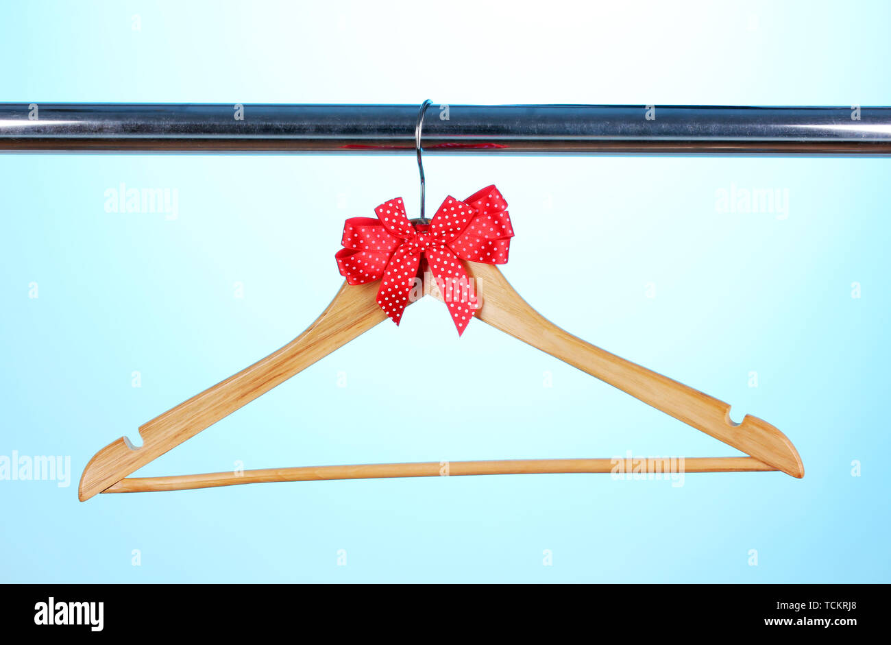 Beautiful red bow hanging on wooden hanger on blue background Stock Photo