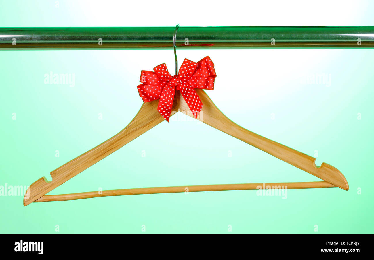 Beautiful red bow hanging on wooden hanger on green background Stock Photo